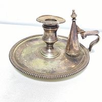 Silver plated early English style candlestick with snuffer, showing hallmarks and the round base with decorative border.