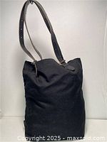 Side and angled views of the black canvas bag with leather straps and buckle details