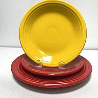 Three Fiesta plates stacked; two yellow side plates on top and one red dinner plate at the bottom.