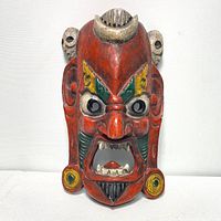 Front view of hand carved and painted wooden Bhairava mask, bright colors and fierce expression clearly visible