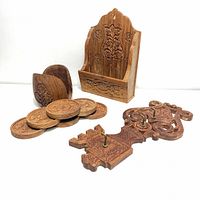 Photo showcasing three carved teakwood items: letter/paper holder, coaster set with holder, and ornate key-shaped key hanger.