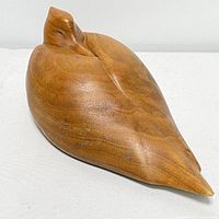 Front angled view of hand carved wood bird decoy showing smooth surface and closed bird eyes.