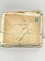 Front view of a bundle of yellowed envelopes tied with string, showing postmarked stamps and handwritten address to Mrs. Harry Clarke.