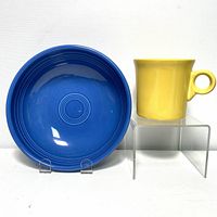 Side-by-side view of a lapis blue bistro bowl and a yellow mug on clear stands.