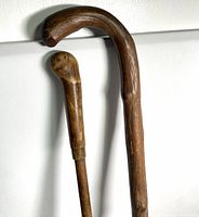 Close view of both wooden canes showing curved bentwood handle and club handle