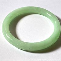 Top view of the jade-colored Peking glass bangle bracelet on a white background showing its smooth polished surface.