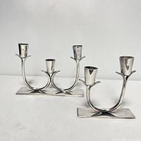 Front view of the three-arm and two-arm silver plated candelabras showing their overall design and condition.