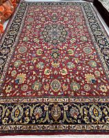 Full view of the rug showing the red field, central medallion and navy blue borders
