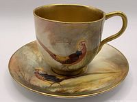 Cup and saucer showing pheasant scene and gilding
