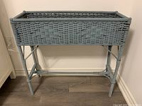 Front view of antique wicker planter showing overall construction and dusty blue paint.