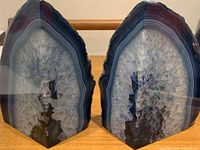 Front view of both blue agate bookends side by side, showing rough natural edges and crystalline centers.