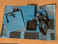 Overall view of the Birks ring box and wrapping items including the small paper bag, larger paper bag folded tissue paper, ribbon, and ring box open and closed arrangements.