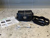 Manuals, carry case, wrist strap, USB cable arranged on countertop