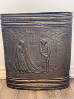 Front side of the copper umbrella stand showing the full embossed scene with two people and surrounding details including window and wall.
