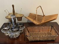 Photo showing the entire lot including wooden condiment caddy with aluminum cups and spoons, folding bamboo basket, matchstick bamboo basket, and metal cocktail glass holder with glass cups.