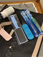 Top view of toothbrushes, foot scrubbers, plastic wall mount, and metal hooks on a black fabric organizer background.