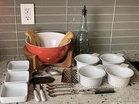 Overview of all items in the lot showing salad bowl with wooden utensils, soup bowls, oil dispenser, grater, nutcracker and decorative sign.