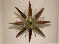 Full view of the starburst clock showing wood and metal starburst pattern with circular gold-tone clock face.