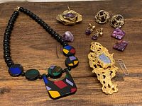 Full lot overview with necklace, several pendants, and three pairs of earrings arranged on wooden surface.