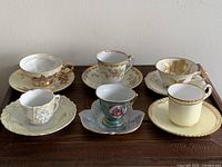 Photo of six vintage demitasse cups and saucers showing variety in design, gold accents, and patterns.