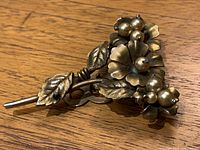 Top view of the vintage scarf pin showing the floral and leaf design with pearl-like beads.