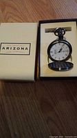 Arizona Jean Company branded box with the pocket watch showing the clock face inside.