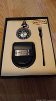 Complete view of Arizona Jeans Company pocket watch gift set including pocket watch, leather case, and watch key in original box.