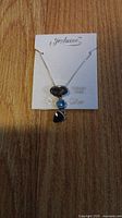 Photo of Fezlaine sterling silver necklace with three gemstone pendants on display card, showing chain and pendants.