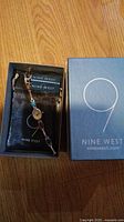 Photo of the Nine West women's wristwatch in original box with tags, showing silver-tone band with turquoise and red stones.