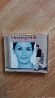 Front cover of Notting Hill CD soundtrack showing close-up photo of actress and smaller figure of actor walking beside her face