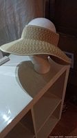 Front and side views of a brand new wide brim straw sun hat on a mannequin head