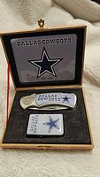Knife and lighter set shown in wooden display box with Dallas Cowboys branding inside lid.