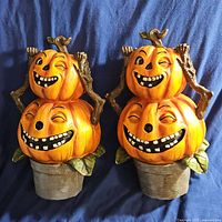 Two identical Halloween decor pieces featuring two smiling and winking stacked pumpkins with green leaf base on blue background.