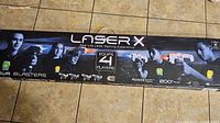 Full box of Laser X laser tag blasters showing four players and product name.