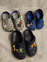 Top-down view of all three pairs of kids Crocs, showing the colors and attached Jibbitz charms.