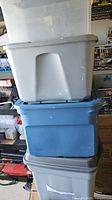 Stack of three plastic storage totes: translucent white top, blue middle, grey bottom, all with lids