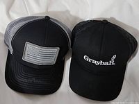 Pair of snapback hats side by side on white surface, one with American flag patch and one with Graybar logo