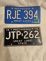 Front side of two vintage Michigan license plates showing embossed text and color with some wear.