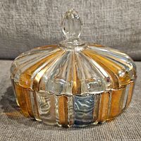 Side view showing ridged clear and amber tinted glass candy dish with a lid and knob handle