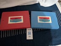 Two rectangular plastic game cases in red and blue with Battleship logo labels on top.