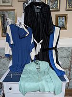 Four vintage 1990s clothing items displayed, three dresses and one jacket, showing belts and jacket clasp details.