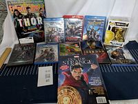Full view of Marvel movies DVDs and Blu-rays, collector books and Funko Pop figure of Doctor Strange, well arranged on a cloth surface.