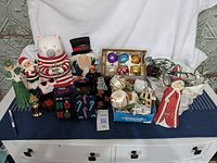 Full lot showing assorted Christmas decorations including cookie jar, figurines, boxed and loose ornaments, string lights, holiday socks, and brass bell.
