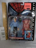 Full view of the sealed Norman Osborn action figure in original packaging showing setup with mask and chair.