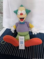 Front view of Krusty the Clown doll sitting showing full figure, clothing details, and face.