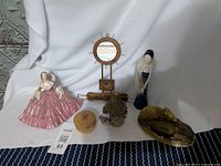 Photo showing full lot arrangement on white and blue cloth backing with all six items visible: pink ceramic lady jewelry holder, alabaster jar, wooden mirror jewelry stand, birdhouse trinket holder, deer ring holder, flapper ceramic lady
