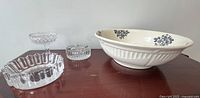 Photo of antique ironstone basin with visible crazing and blue floral pattern. Also shows three glass ashtrays and one crystal candy dish on wooden surface.