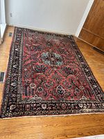 Full view revealing red field, navy floral vine pattern, overall wear