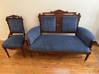 Front view of antique Victorian wooden framed settee and matching chair with blue velvet upholstery.