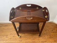 Full view of the tea cart with the removable tray lifted and resting on the cart frame showing the brass hinges and cutout hand grips.